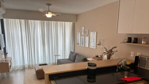 A modern kitchen with a built-in stove, a sink, and a countertop. There is a dining area with a sofa and a coffee table. - Studio 203 São Paulo prox Allianz Unimed (São Paulo)