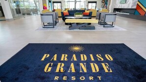 Un hall d'hôtel avec un tapis bleu sur lequel est inscrit le texte « PARADISO GRANDE RESORT ».
