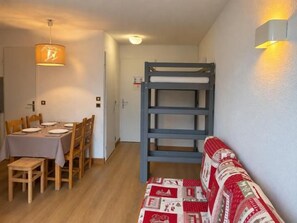 A room with a bunk bed, a dining table with chairs, and a sofa. - 100m from ski slopes, 1st floor, balcony, tv, 25m², Val Thorens (Val Thorens)