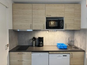 A compact kitchen with a microwave, coffee maker, and dishwasher.