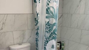Ein Badezimmer mit Toilette, einer Badewanne und einer Duschvorhang mit Blumenmuster.