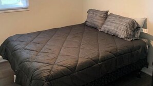 Ein Schlafzimmer mit einem Bett, einem Deckenventilator und einem Fenster mit Jalousien.