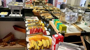 A buffet with various food items and beverages, including fruits, bread, and a milk carton. - Pousada Cunha (Caldas Novas)