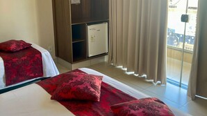 A hotel room with two beds, a wardrobe, a minibar, and a view of the outside. - Pousada Cunha (Caldas Novas)