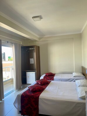 A hotel room with two beds, a wardrobe, a refrigerator, and a sliding glass door to the outside. - Pousada Cunha (Caldas Novas)