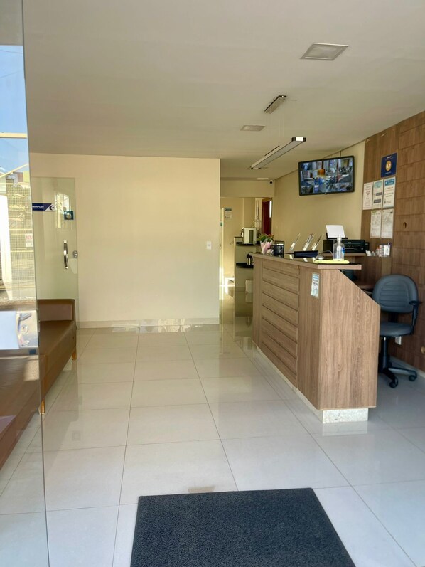 A reception area with a wooden desk, a computer, and a television mounted on the wall.