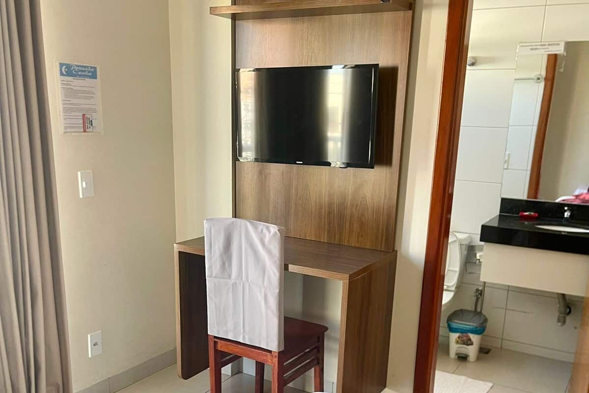 A hotel room with a bed, a desk with a chair, a television, and a mirror.