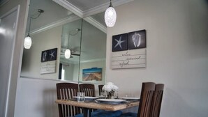 Un comedor con una mesa de madera, sillas con cojines azules y una araña.