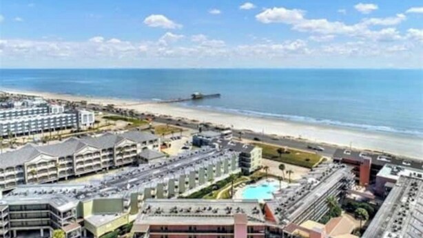 Un hotel frente al mar con varias edificaciones, una playa y un muelle.
