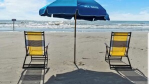 A beach with two yellow beach chairs and a blue umbrella. - Isle B Back Seawall Gulf & Pool View! Come Chillax (Galveston)