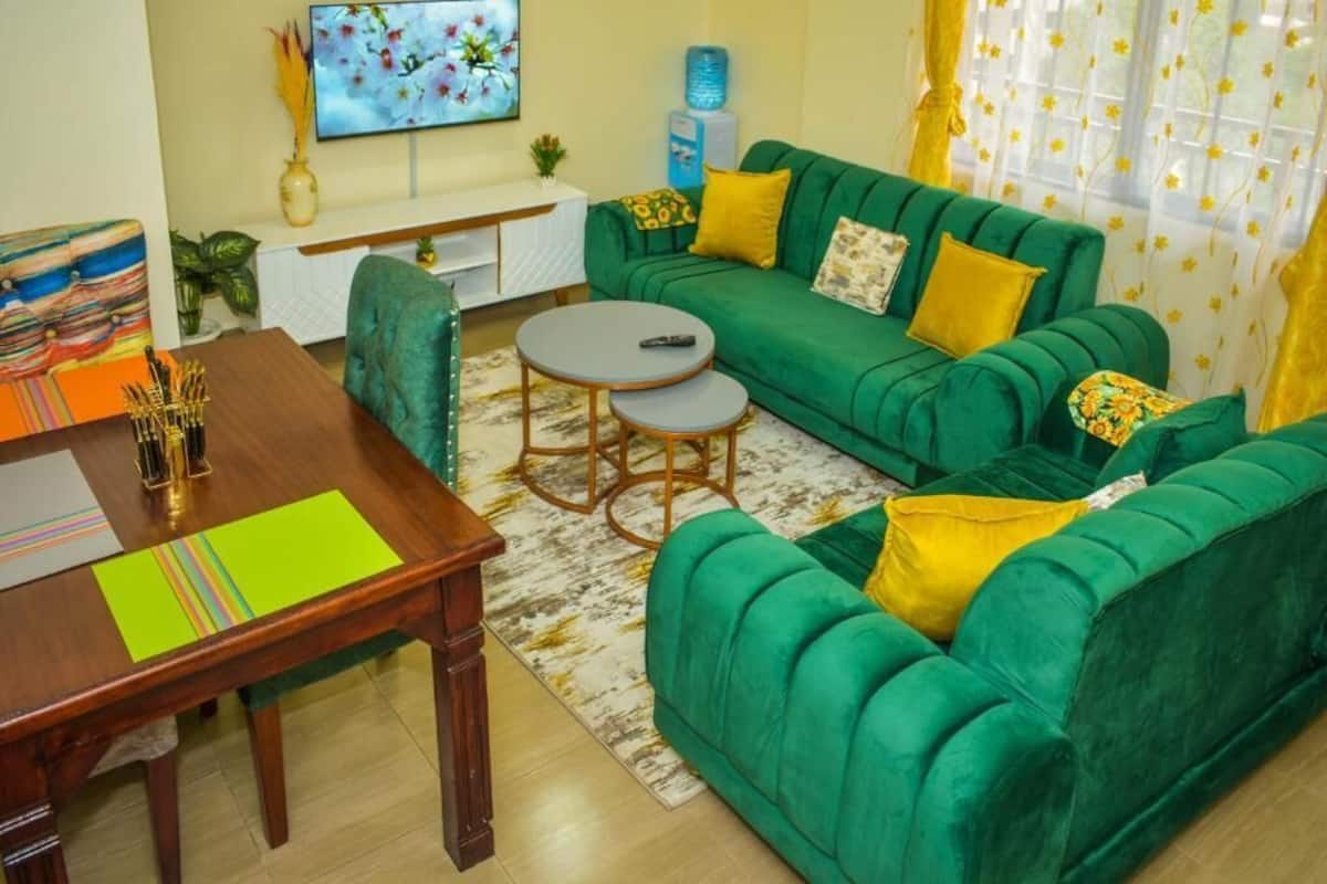 Una sala de estar con un sofá verde, una mesa de centro de madera y un televisor en la pared.