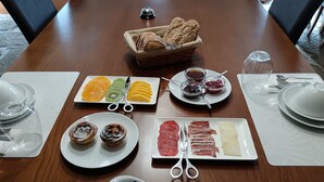 A dining table with various food items, including bread, fruits, jams, pastries, and cheese. - Casa dos Poços (Figueira de Castelo Rodrigo)