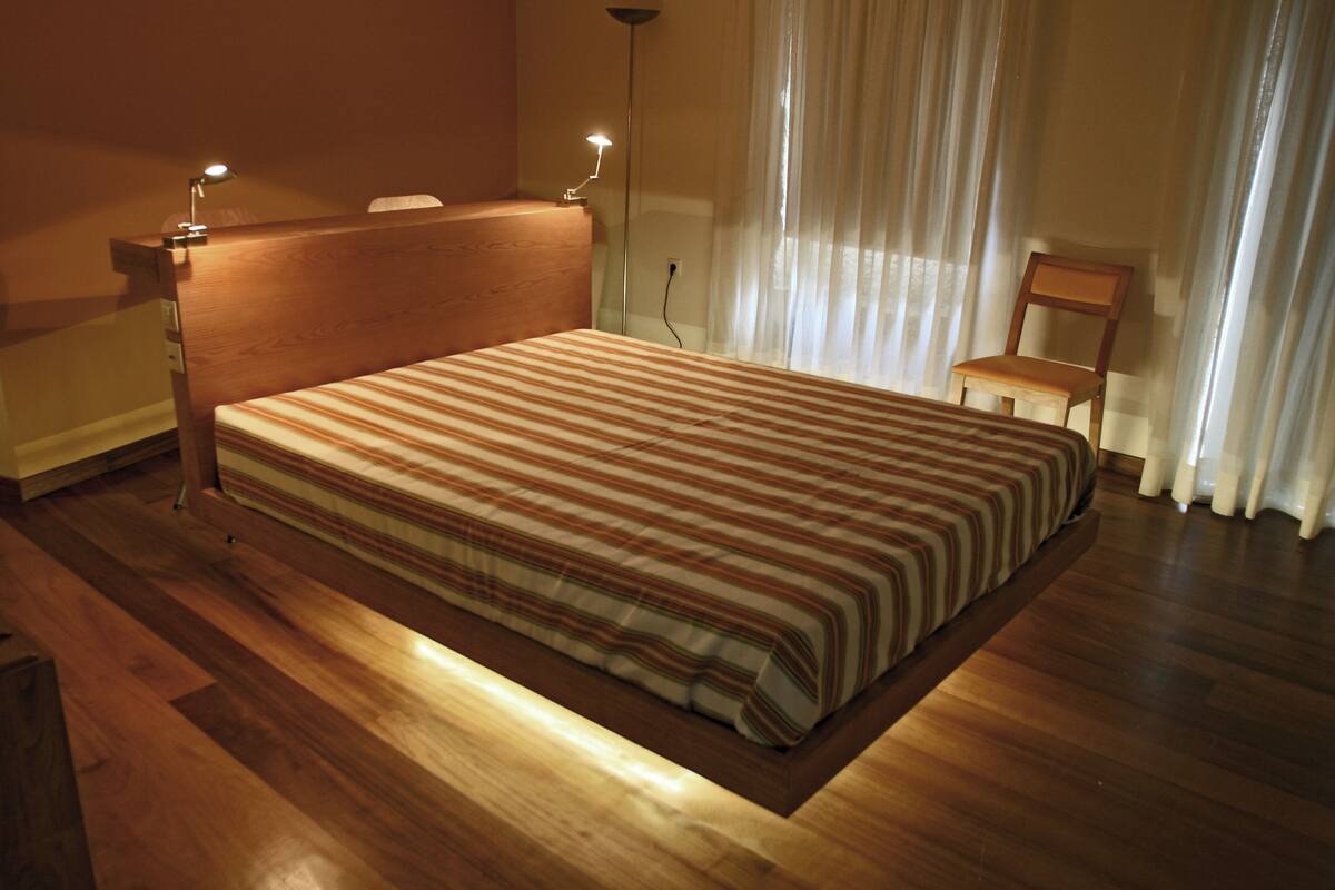 Un lit bien fait, avec une couvre-lit à rayures, une tête de lit en bois et des lampes de chevet.