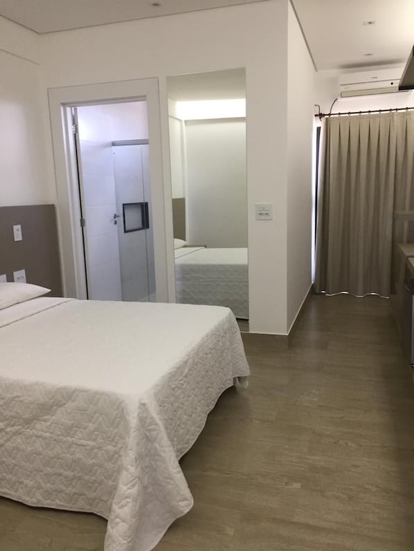 Ein Hotelzimmer mit einem Bett, einer Tür zu einem anderen Raum und einem Badezimmer mit Duschvorhang.