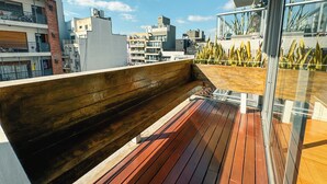 A wooden deck with a glass railing overlooking a cityscape. - BT Homes - Palermo, Soler (Buenos Aires)
