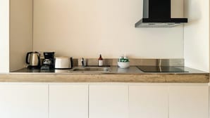 A kitchen with a stainless steel sink, a kettle, a coffee maker, and a bowl of green tea packets. - BT Homes - Palermo, Soler (Buenos Aires)