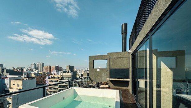 A rooftop pool with a city view, a modern building with large windows, and a chimney. - BT Homes - Palermo, Soler (Buenos Aires)