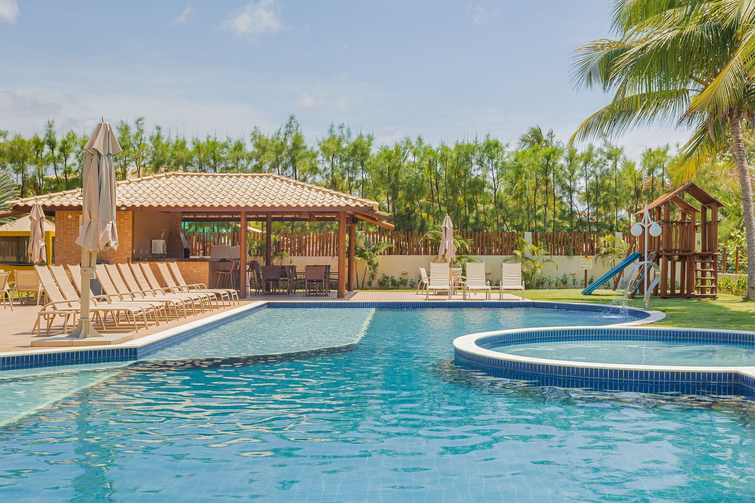 A swimming pool with lounge chairs and a covered seating area.