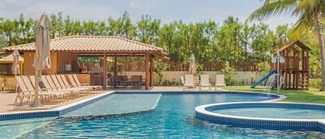 A swimming pool with lounge chairs and a covered seating area.