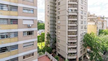 Un edificio residenziale a più piani con balconi, condizionatori e un cortile con vegetazione.