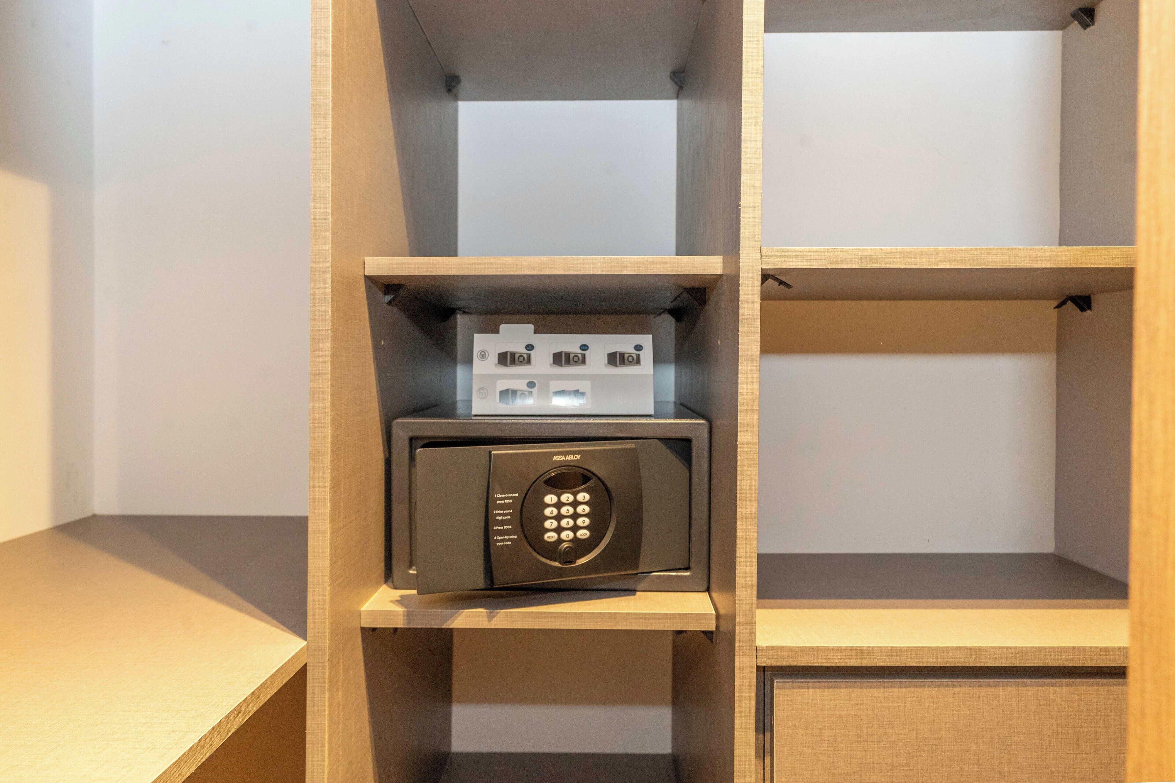 Une chambre d’hôtel équipée d’une étagère en bois où se trouvent un four à micro-ondes et un petit appareil électroménager.