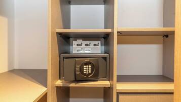 A hotel room with a wooden shelf unit containing a microwave and a small appliance.