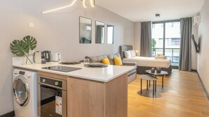 Ein modernes Hotelzimmer mit einer Küchenzeile, einem Essbereich und einem Bett.