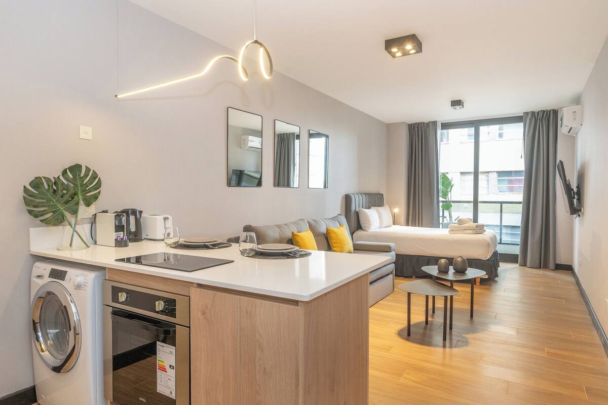 Une chambre d’hôtel moderne équipée d’une kitchenette, d’un coin repas et d’un lit.