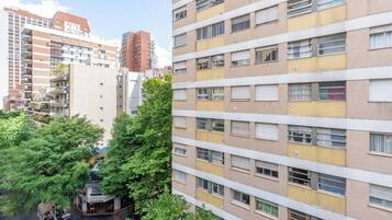Un edificio residencial de varios pisos con balcones, una zona comercial en la planta baja y zonas verdes circundantes.