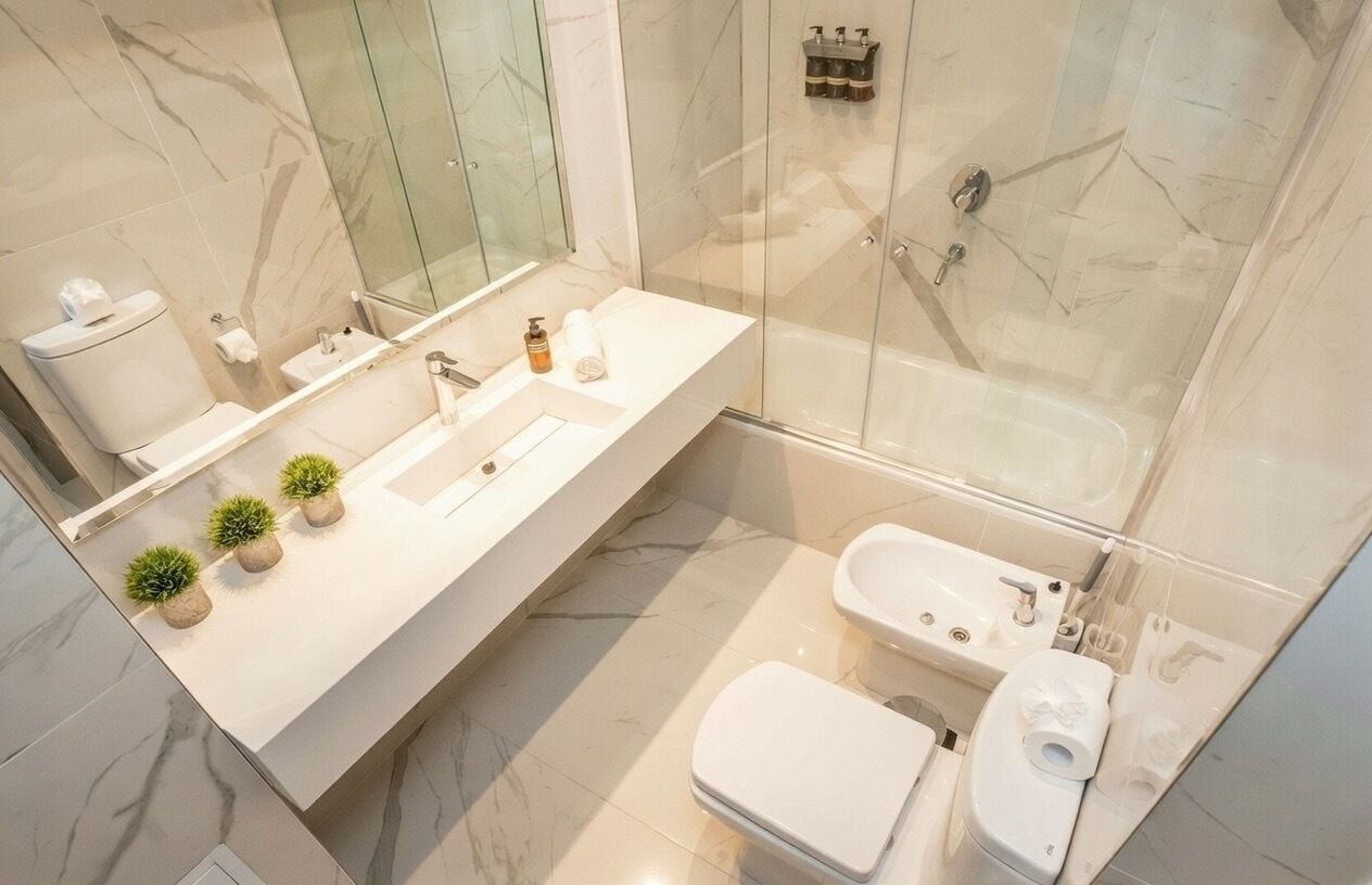 A modern bathroom with a glass-enclosed shower, a white sink, and a toilet.