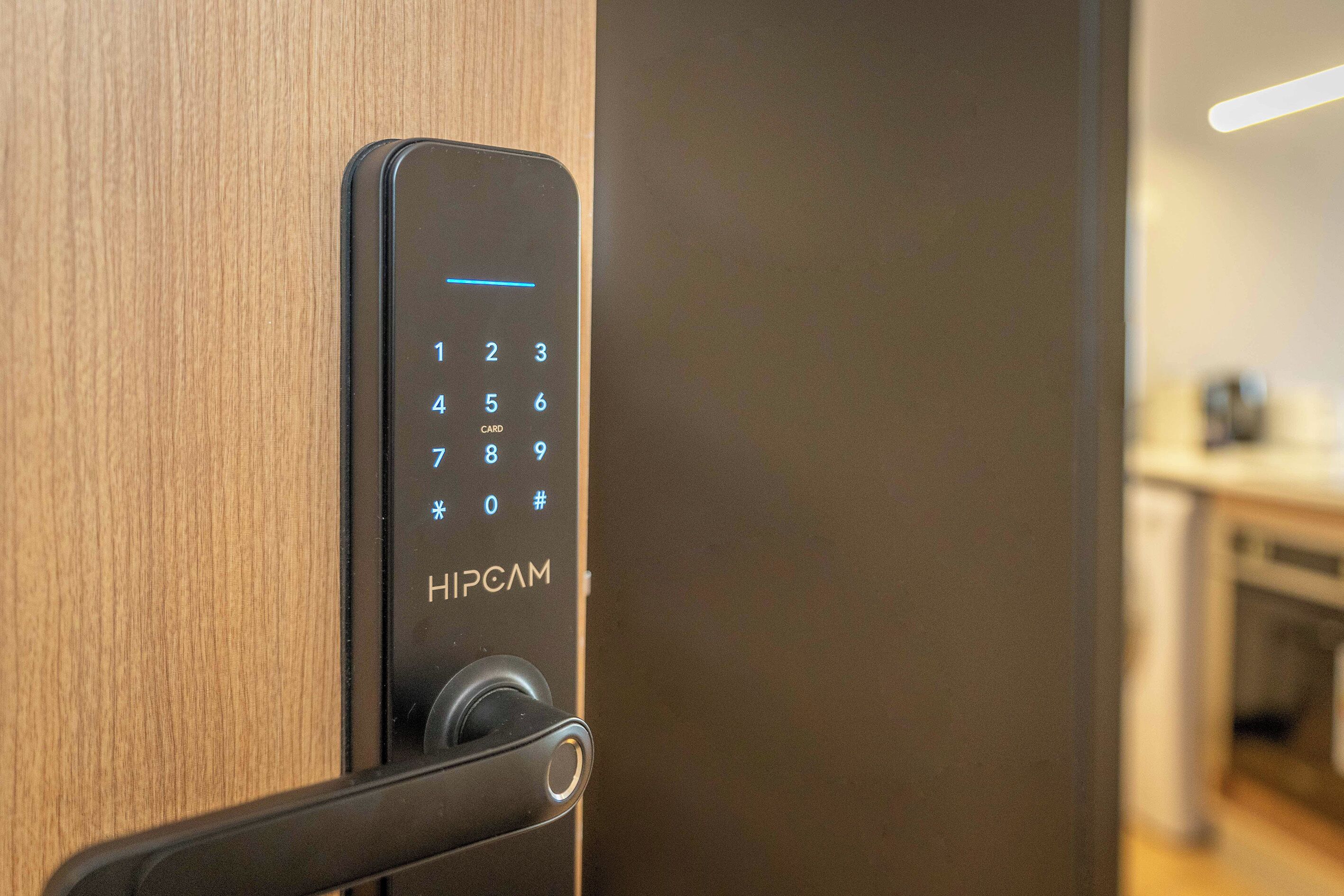 A digital keypad lock on a wooden door, likely for a hotel room.