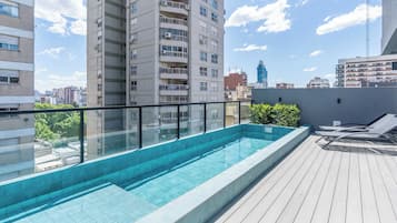 Una piscina al aire libre, sombrillas, sillones reclinables de piscina