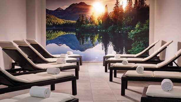 Une salle de spa équipée de fauteuils inclinables, ornée d’une fresque représentant un lac et des montagnes, et offrant une vue sur le coucher de soleil.
