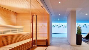 Un espace spa moderne avec des bancs en bois et une cloison en verre.