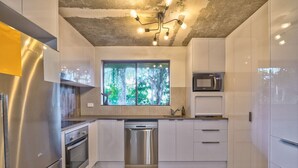 Una cocina moderna con electrodomésticos de acero inoxidable, lavavajillas y armarios blancos.