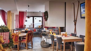 A cozy dining area with wooden tables and chairs, a fireplace, and a view of the snowy landscape. - Holiday apartment with wellness area (St. Michael im Lungau)