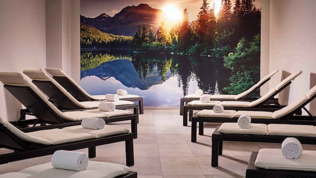 A spa room with reclining chairs, a mural of a lake and mountains, and a view of the sunset. - Holiday apartment with wellness area (St. Michael im Lungau)