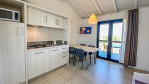 Een moderne keuken met witte kasten, een gasfornuis en een eethoek met een tafel en stoelen.