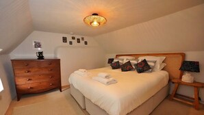 Ein Schlafzimmer mit einem Bett, einem Holzschrank, einem Nachttisch und einer Deckenleuchte.
