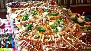 A large, rectangular table covered with a variety of meats and cheeses, set on a checkered tablecloth. - Berggasthof Willy Merkl (Schliersee)