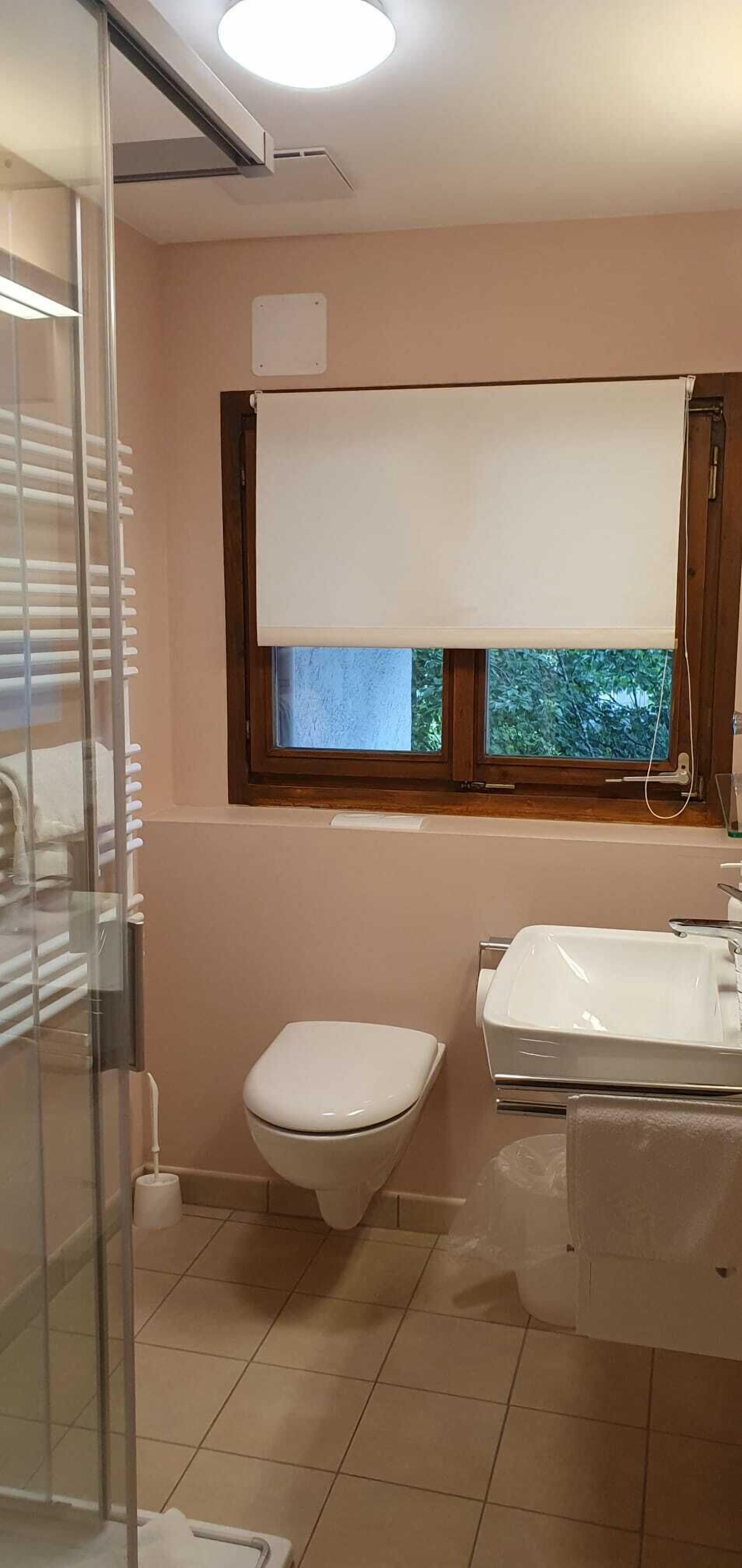 Un baño con inodoro, lavabo y ventana con persiana.