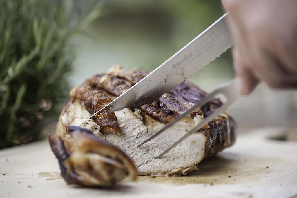 Une personne qui découpe de la viande sur une planche à découper.