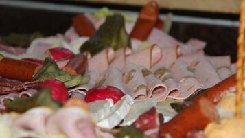 A variety of sliced meats and vegetables on a platter.
