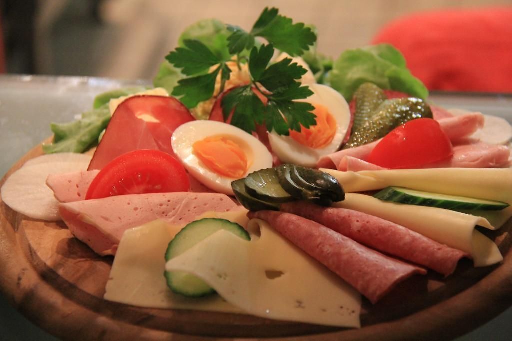 Una tabla de madera con diversos productos de charcutería, como embutidos, quesos y verduras.