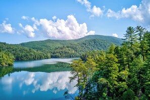 Escape to a serene lake surrounded by lush forested hills, perfect for nature lovers seeking a peaceful retreat.