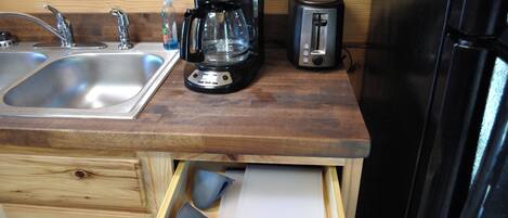 A kitchen with a wooden countertop, a coffee maker, a toaster, and a refrigerator.