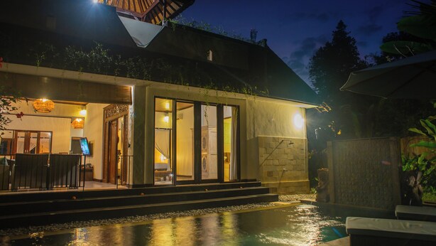 A modern hotel with a swimming pool, outdoor seating, and a well-lit entrance. - Coco Villa (Ubud)