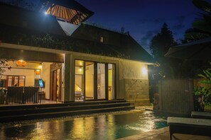 Ein modernes Hotel mit Pool, Sitzgelegenheiten im Freien und einem gut beleuchteten Eingang.