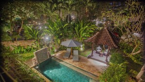 A swimming pool with lounge chairs and a gazebo, surrounded by lush greenery. - Coco Villa (Ubud)
