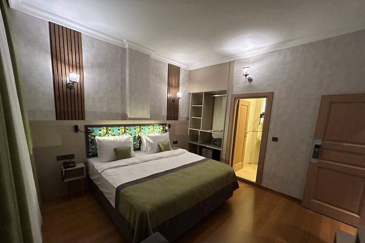 A bedroom with a bed, bedside tables, a wardrobe, a shower area, and a built-in shelving unit.
